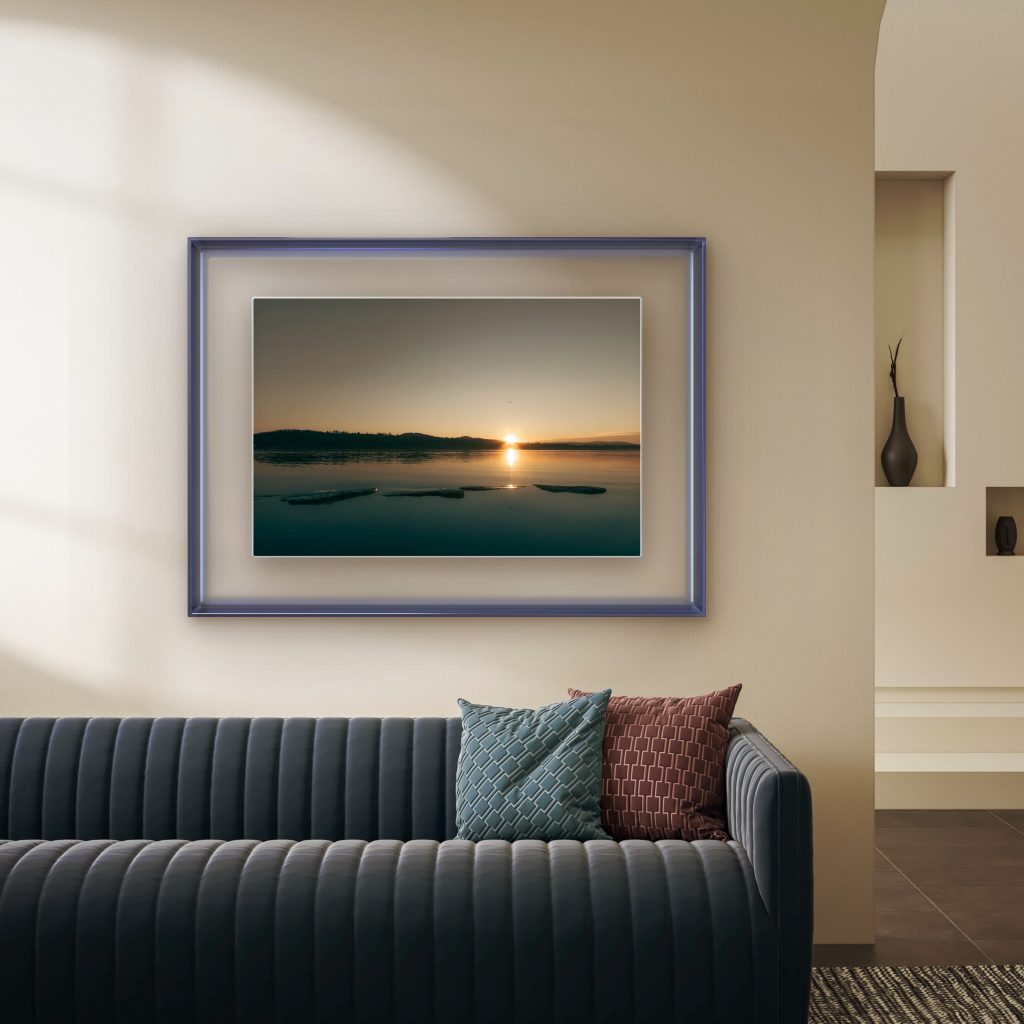 Framed minimalist sunset lake photography displayed in a modern luxury living room interior. Fine art landscape print featuring calm reflective water, stepping stones, and warm golden hour light styled as elegant contemporary wall art for sophisticated home decor and Scandinavian-inspired interiors.