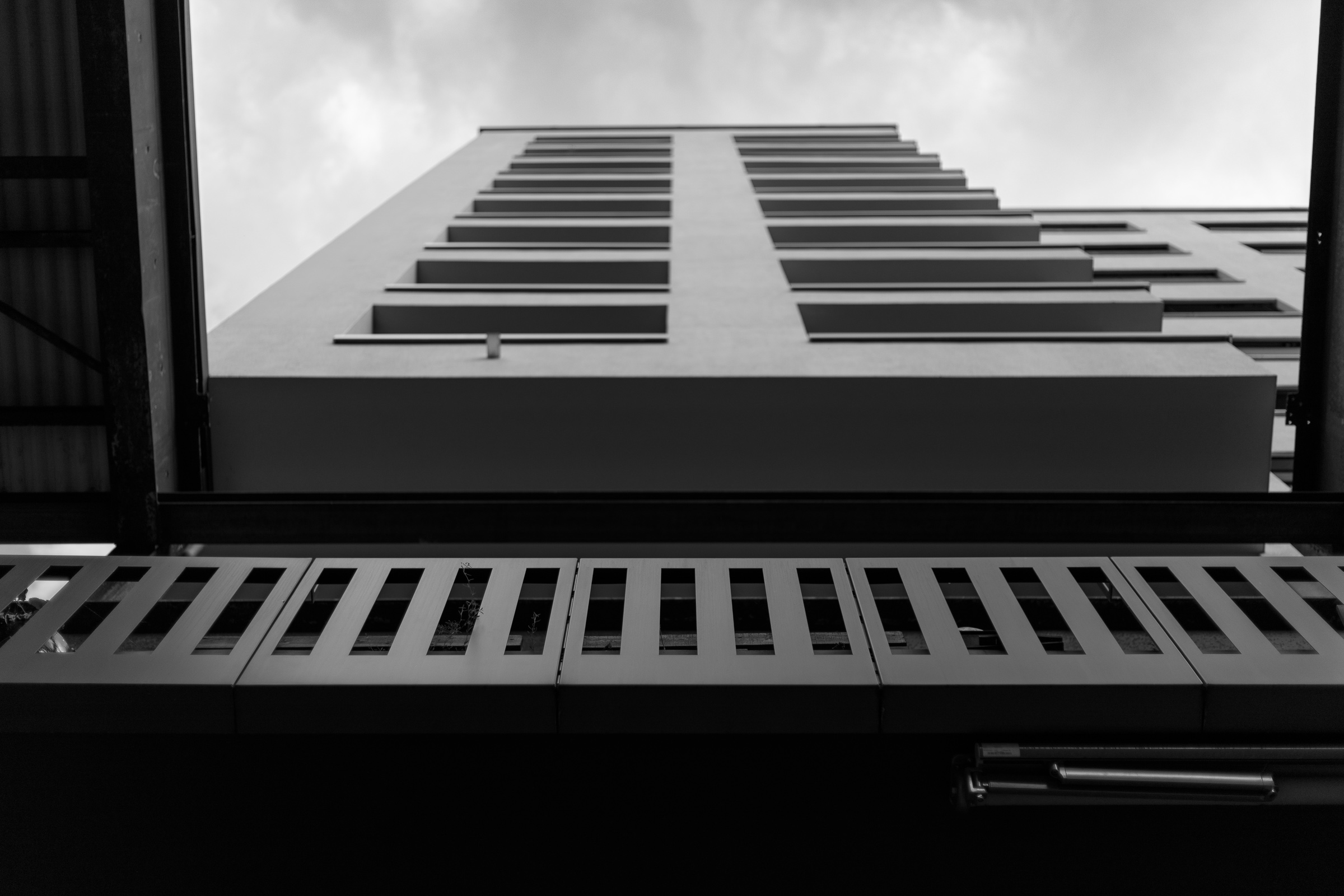 Minimal interior with a large framed black and white architectural print of a modern building seen from below, strong diagonals against a bright sky.